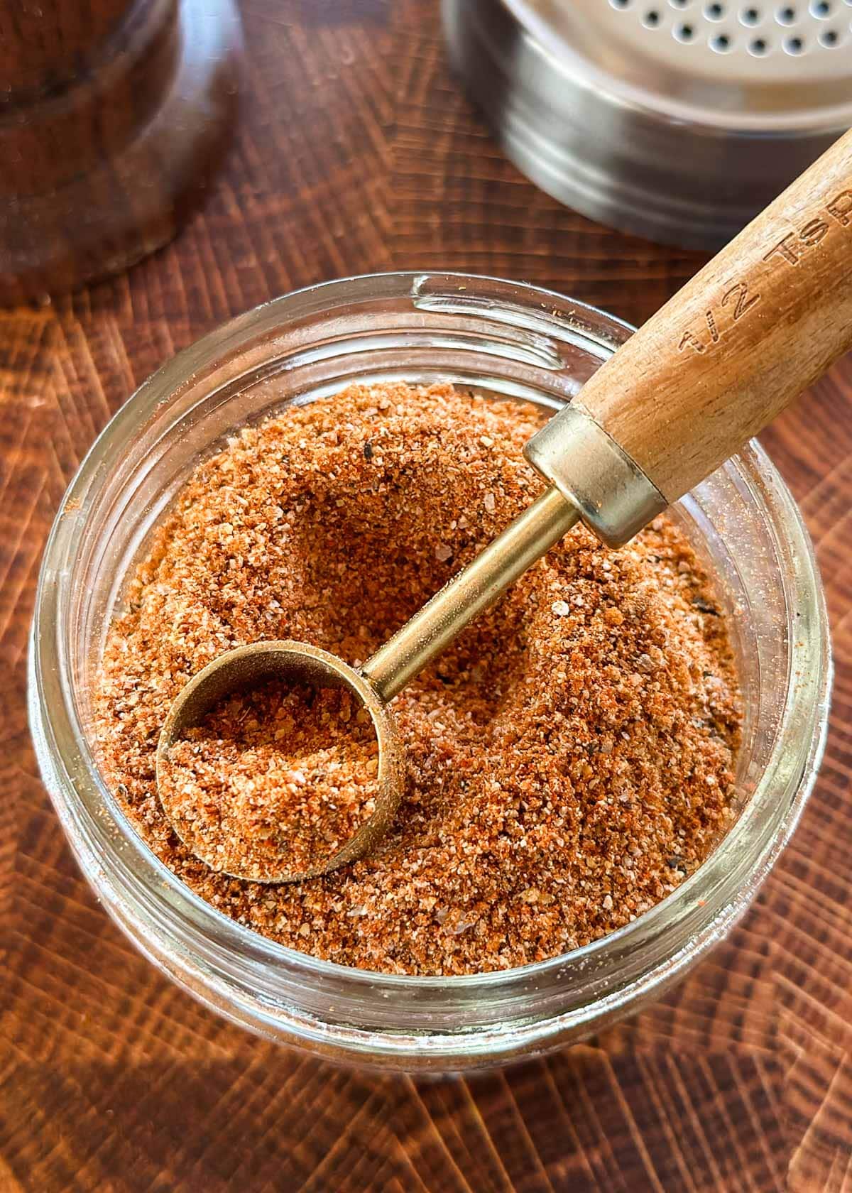 classic burger seasoning in a small glass mason jar with a wood and brass measuring spoon