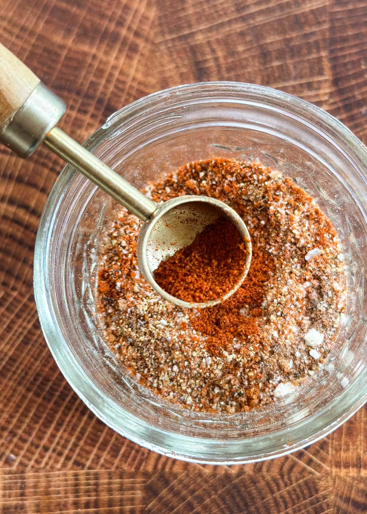 classic burger seasoning in a glass jar with a measuring spoon