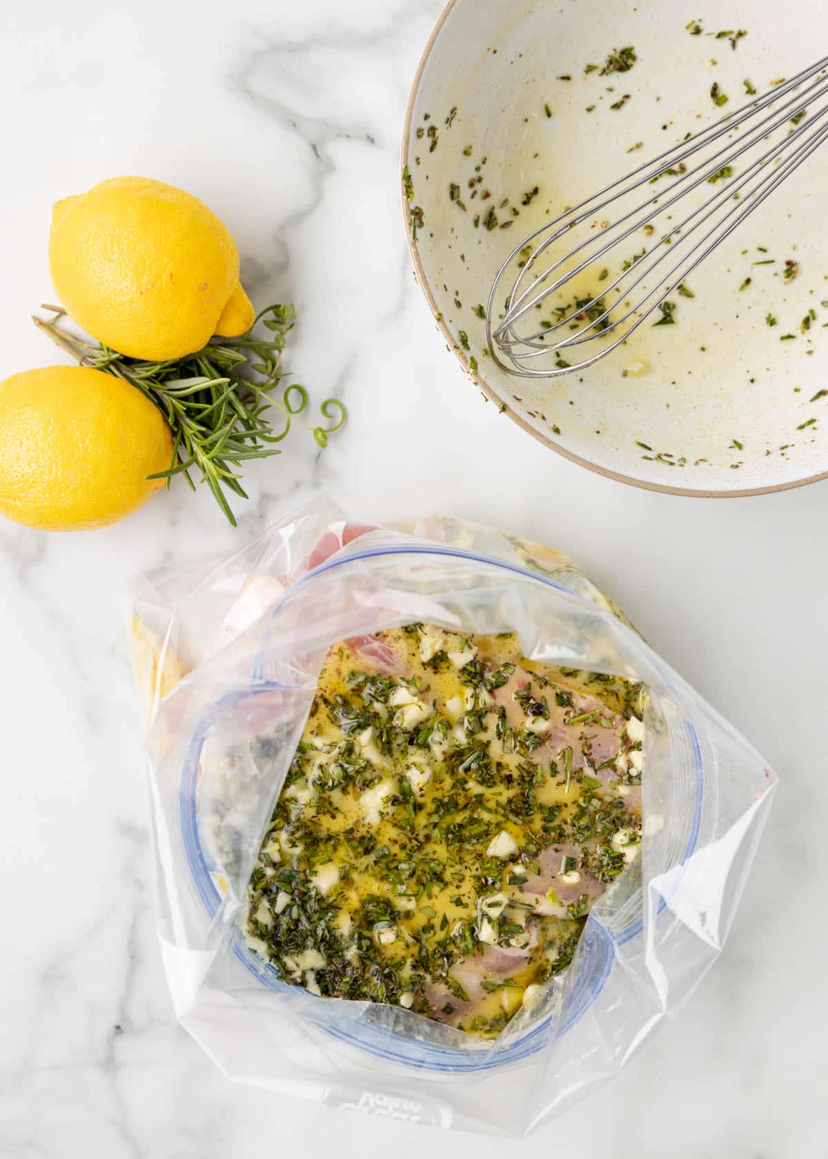 overhead of pork chops covered with lemon herb marinade in an open plastic zip top bag
