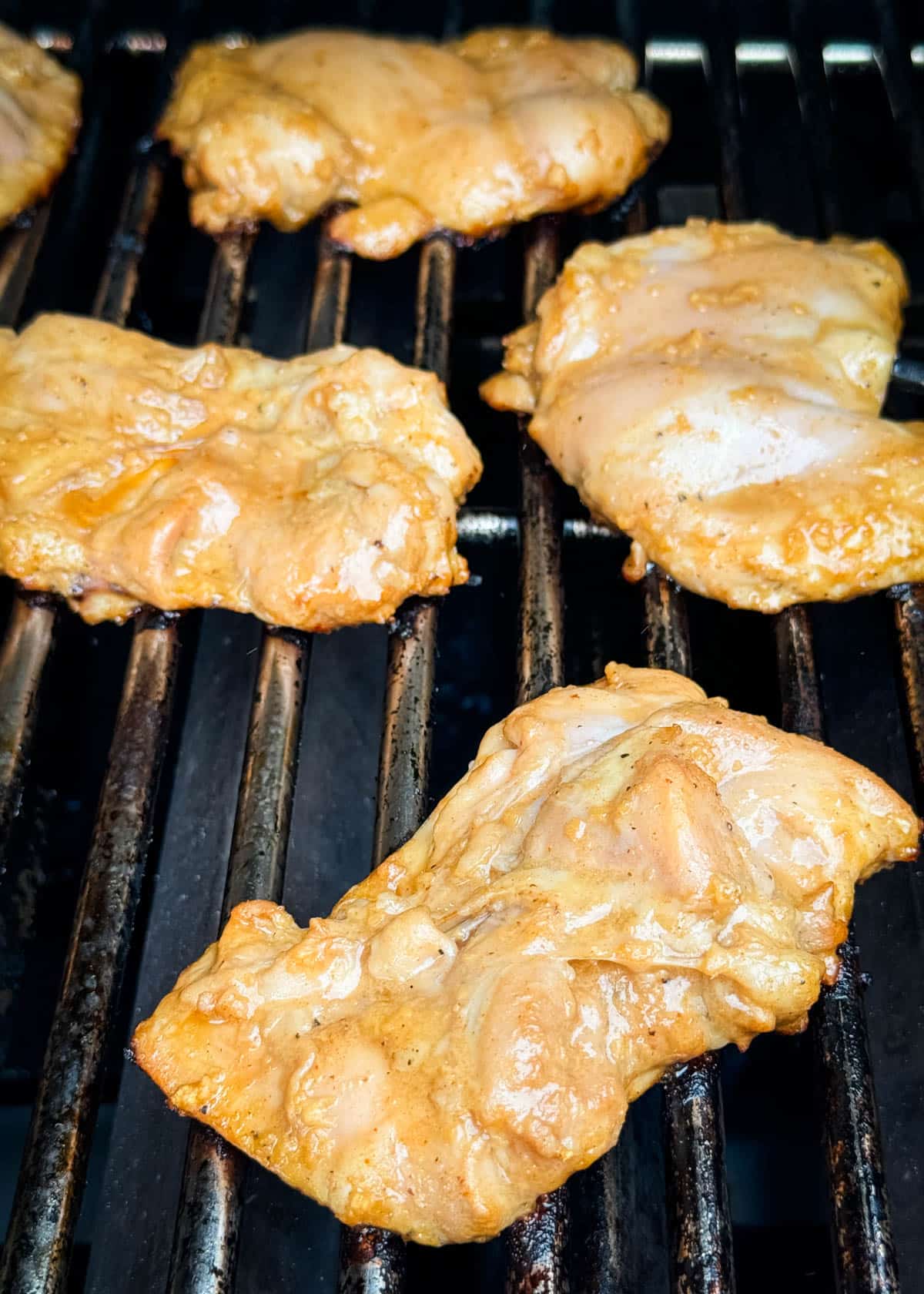 raw marinated bourbon chicken thighs on grill grates