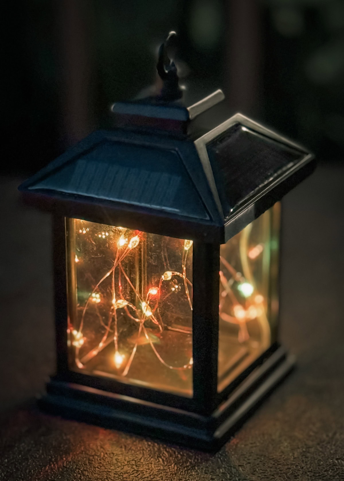 fairy light lantern lit at night on a dark brown outdoor cabinet