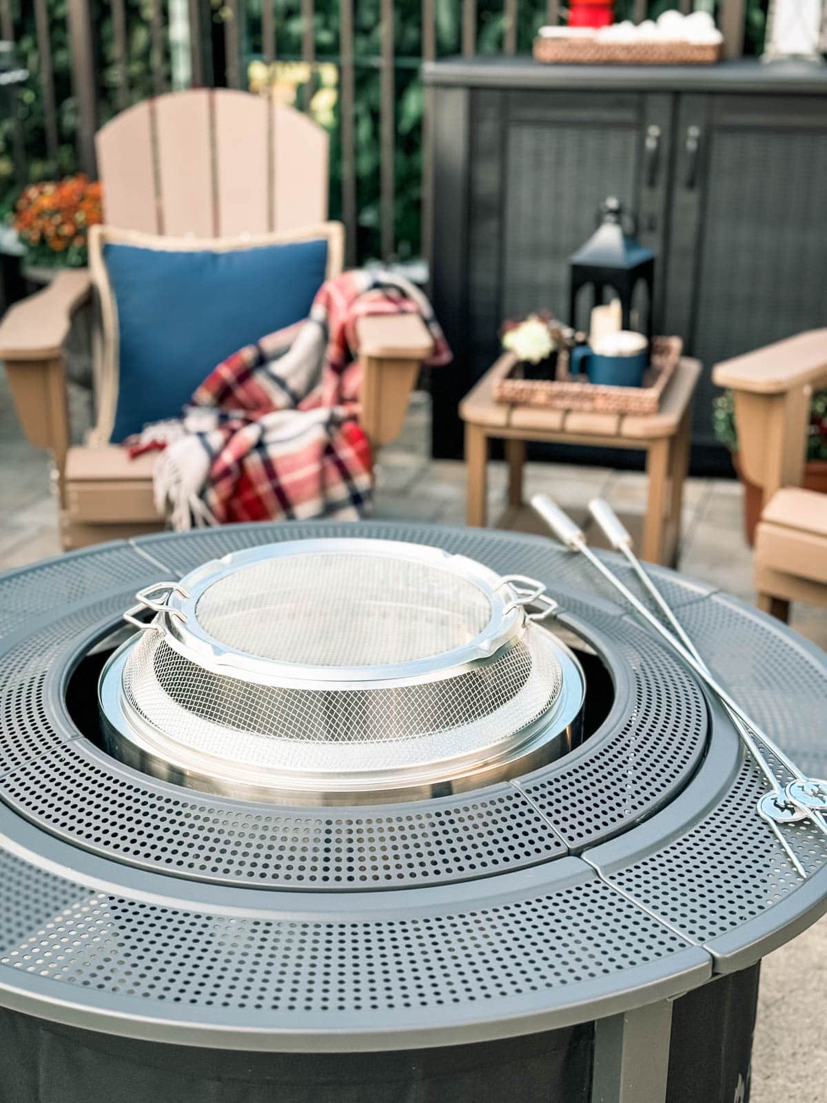 unlit solo stove fire pit in front of a blanket-draped Adirondack chair on a patio
