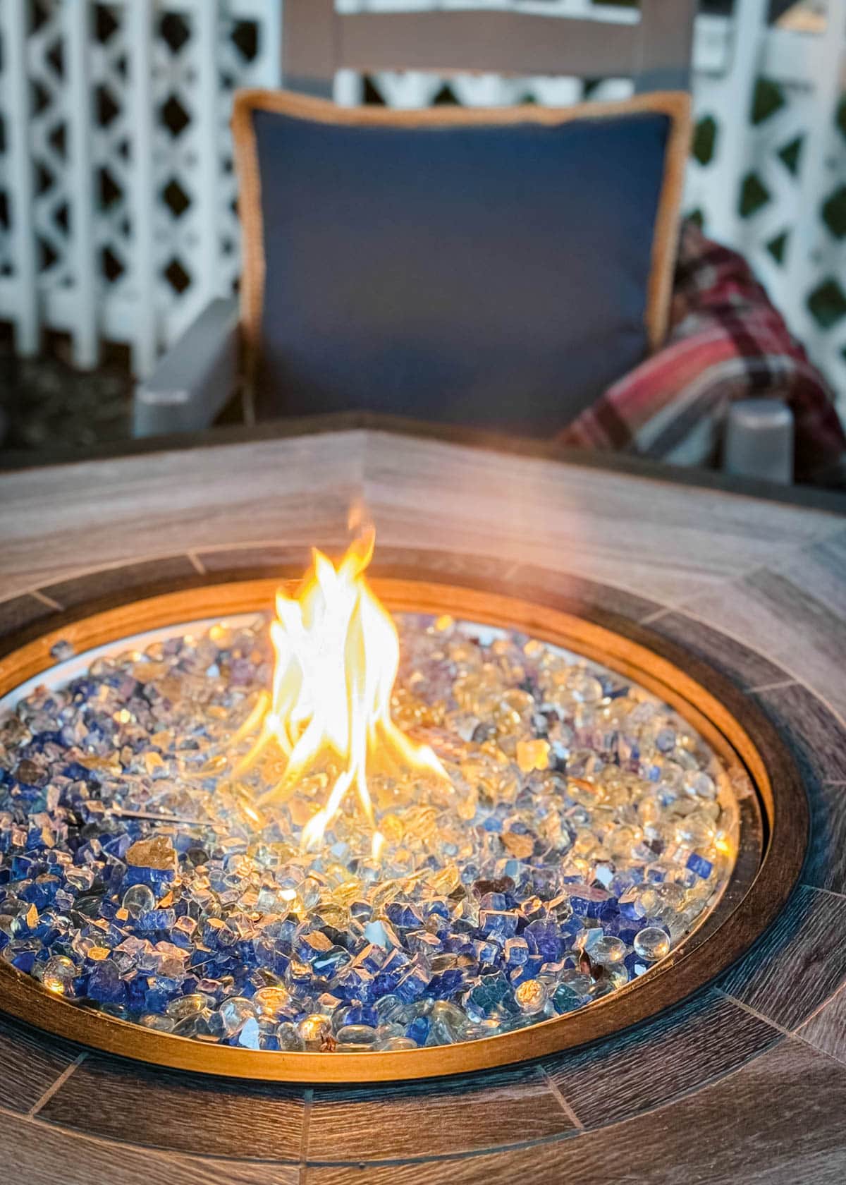 lit fire table with a rocking chair, blue pillow, and wool blanket