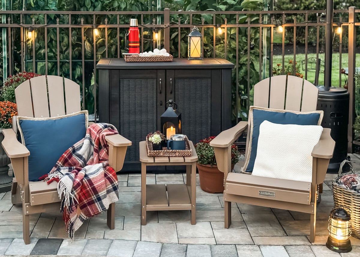 patio set up with adirondack chairs, pillows, blankets and lanterns