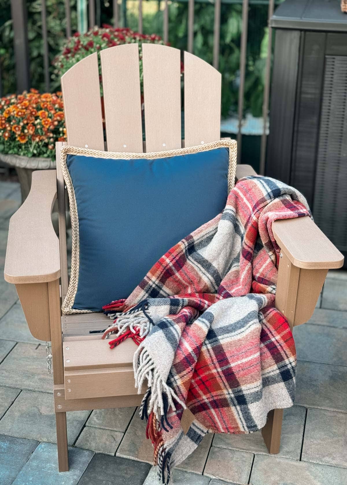 adirondack chair with a blue pillow and draped wool blanket on a stone patio