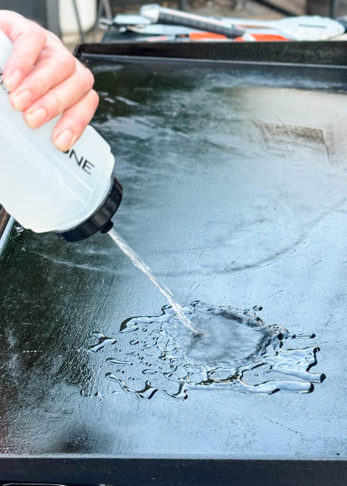 water being squirted onto a warm griddle surface from a squeeze bottle