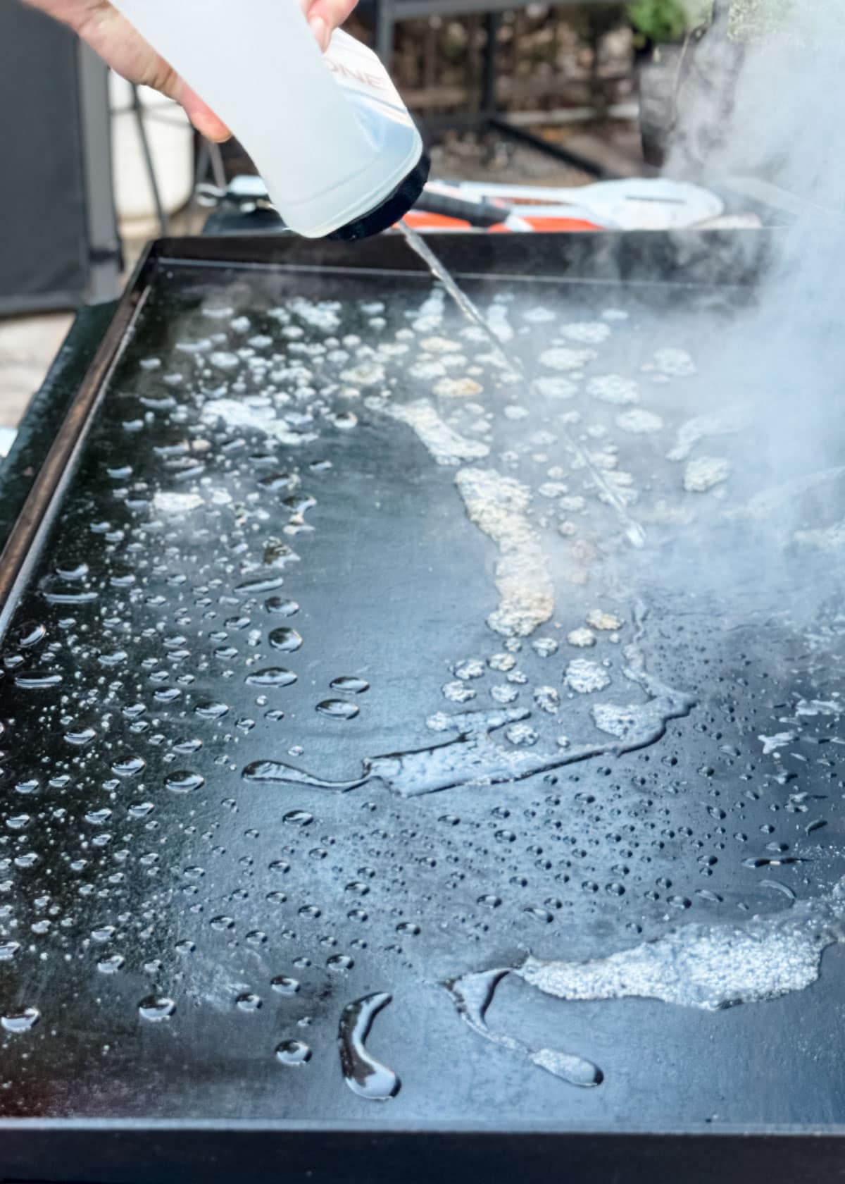 water being squirted onto a warm griddle surface from a squeeze bottle and bubbling up with steam