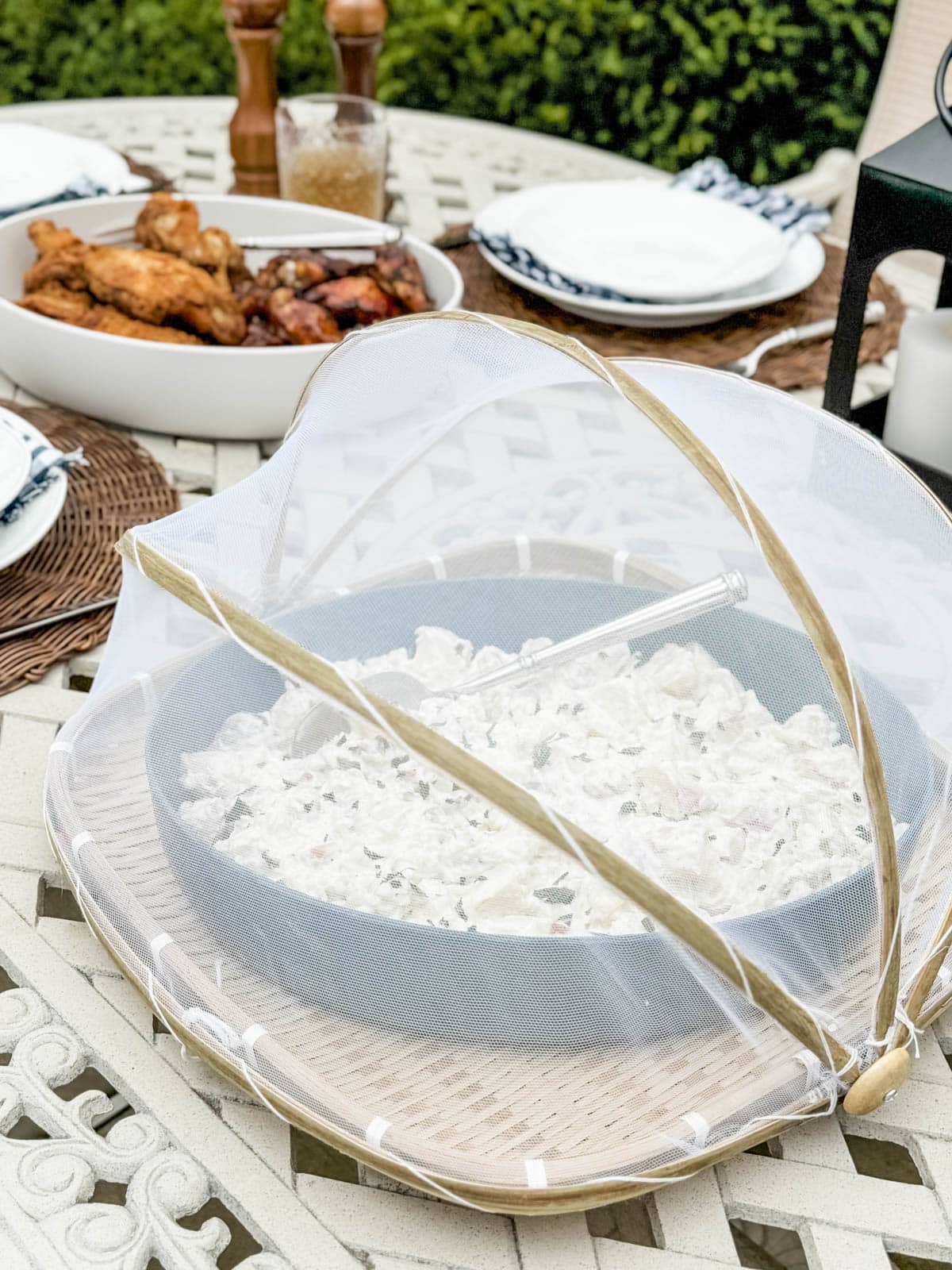 platter of potato salad in a net covered bamboo basket on a picnic table