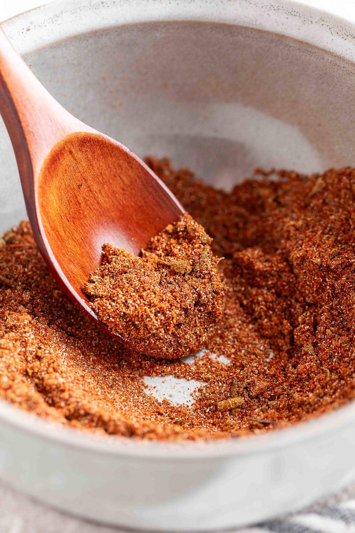 homemade fajita seasoning in a white bowl with a wooden spoon