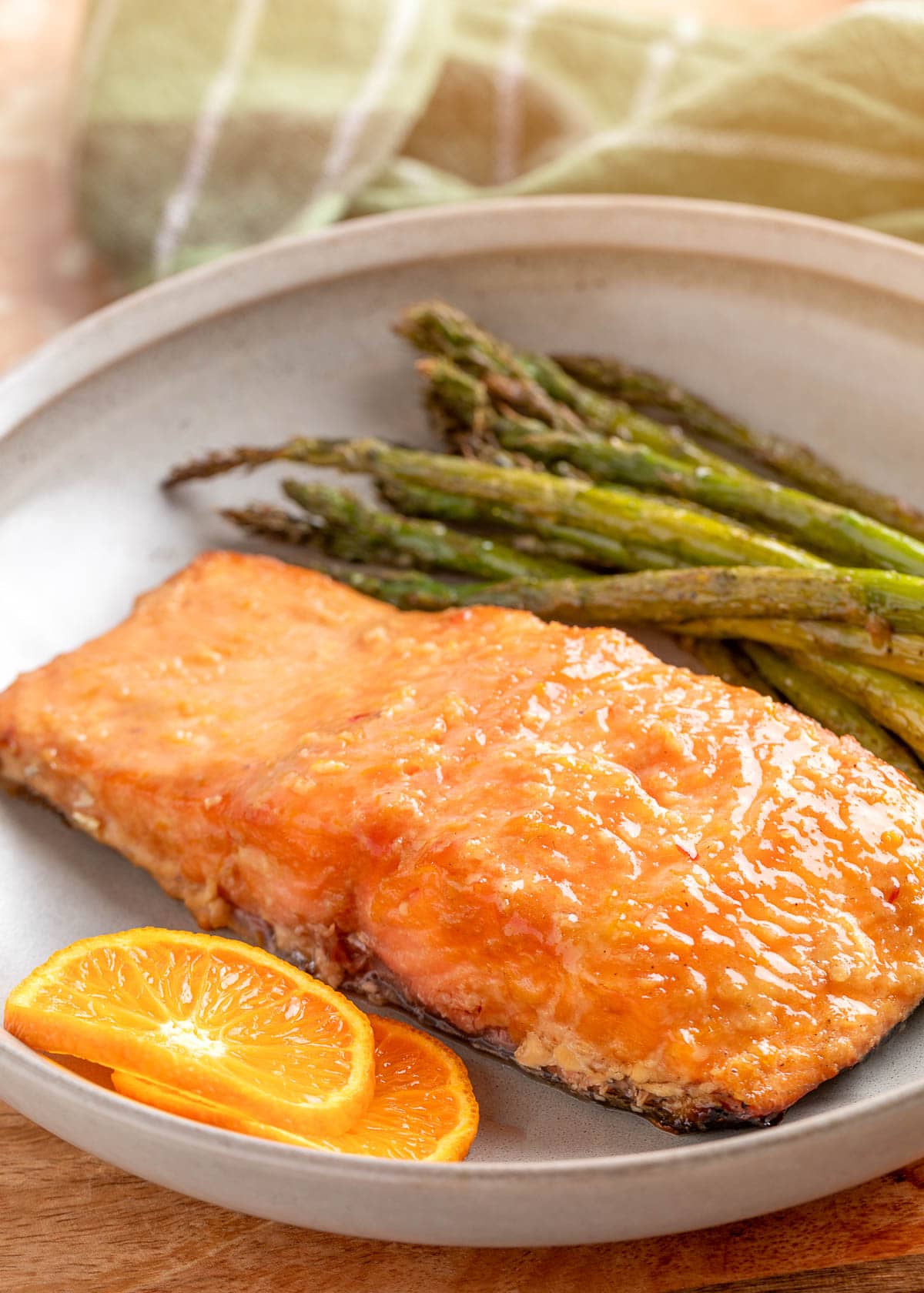 smoked salmon fillet with orange maple bourbon glaze on a plate with grilled asparagus and orange slices
