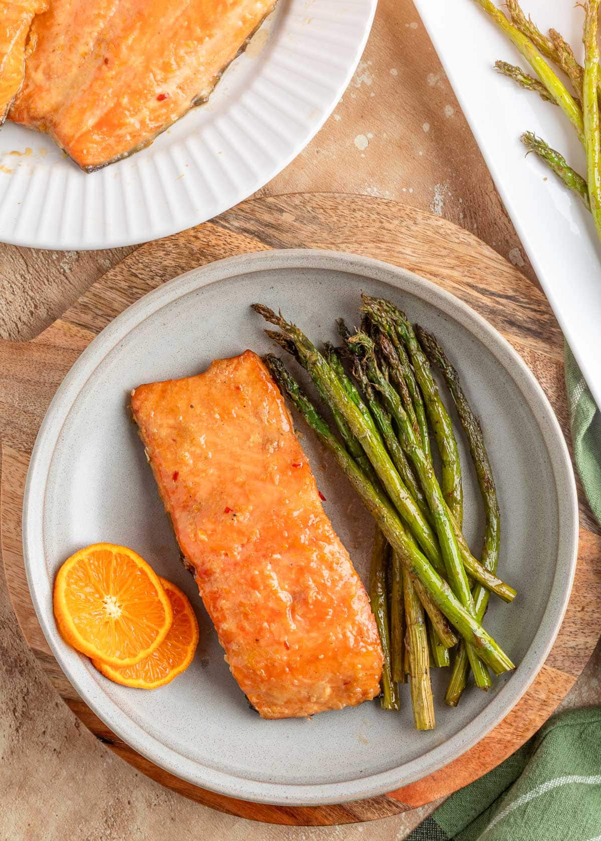 overhead of orange maple bourbon glazed smoked salmon fillet on a plate with asparagus and orange slices