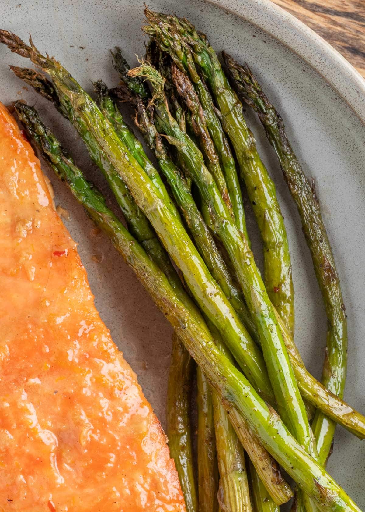 overhead of smoked asparagus on a plate next to a citrus glazed salmon fillet