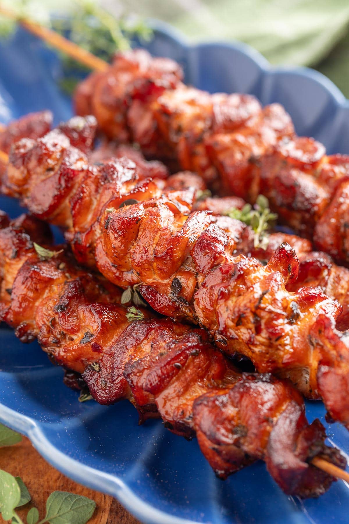 smoked chicken souvlaki skewers on a blue scalloped platter with fresh oregano