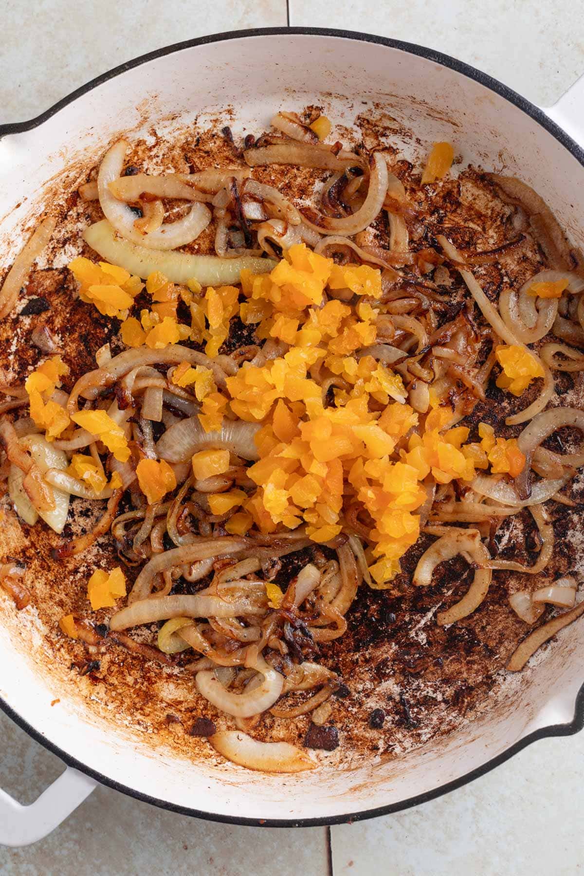 chopped dried apricots in a white skillet with caramelized onions