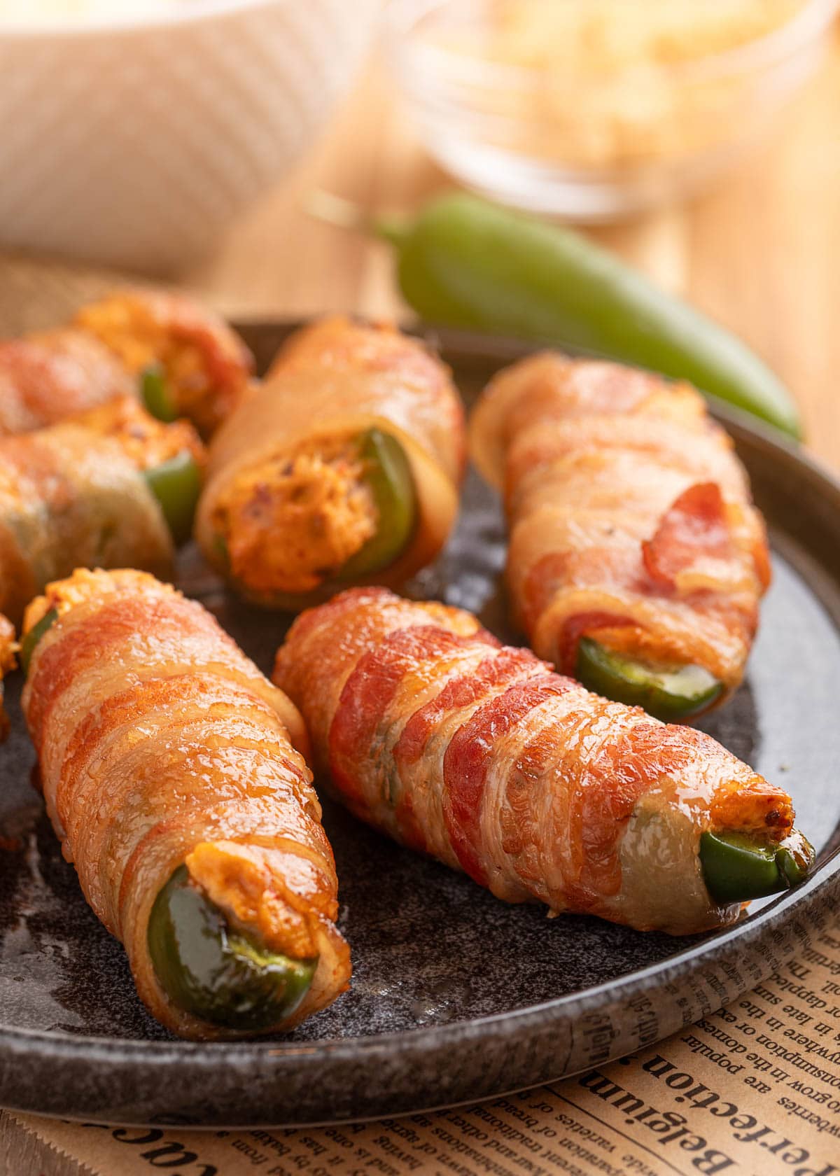 bacon wrapped smoked jalapeno poppers on a dark gray plate