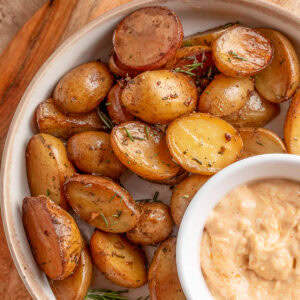 overhead of smoked potatoes with rosemary and garlic on a plate with a bowl of garlic mayo