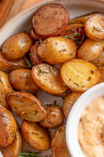 overhead of smoked potatoes with rosemary and garlic on a plate with a bowl of garlic mayo