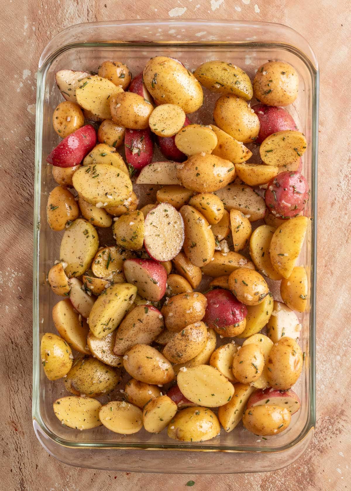 overhead of seasoned halved baby potatoes in a glass baking dish