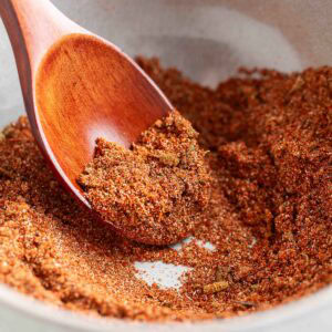 homemade fajita seasoning in a white bowl with a wooden spoon