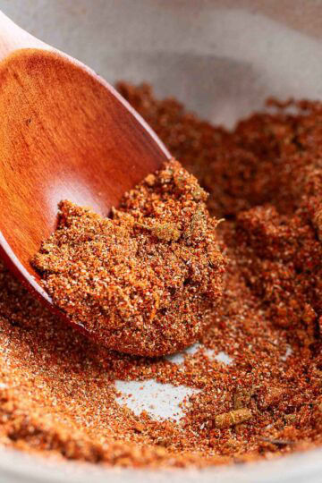 homemade fajita seasoning in a white bowl with a wooden spoon