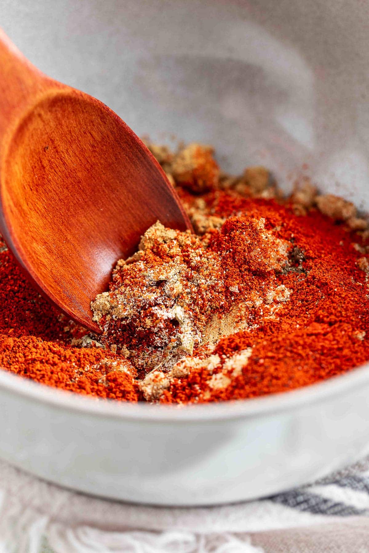 unmixed fajita seasoning in a white bowl with a wood spoon